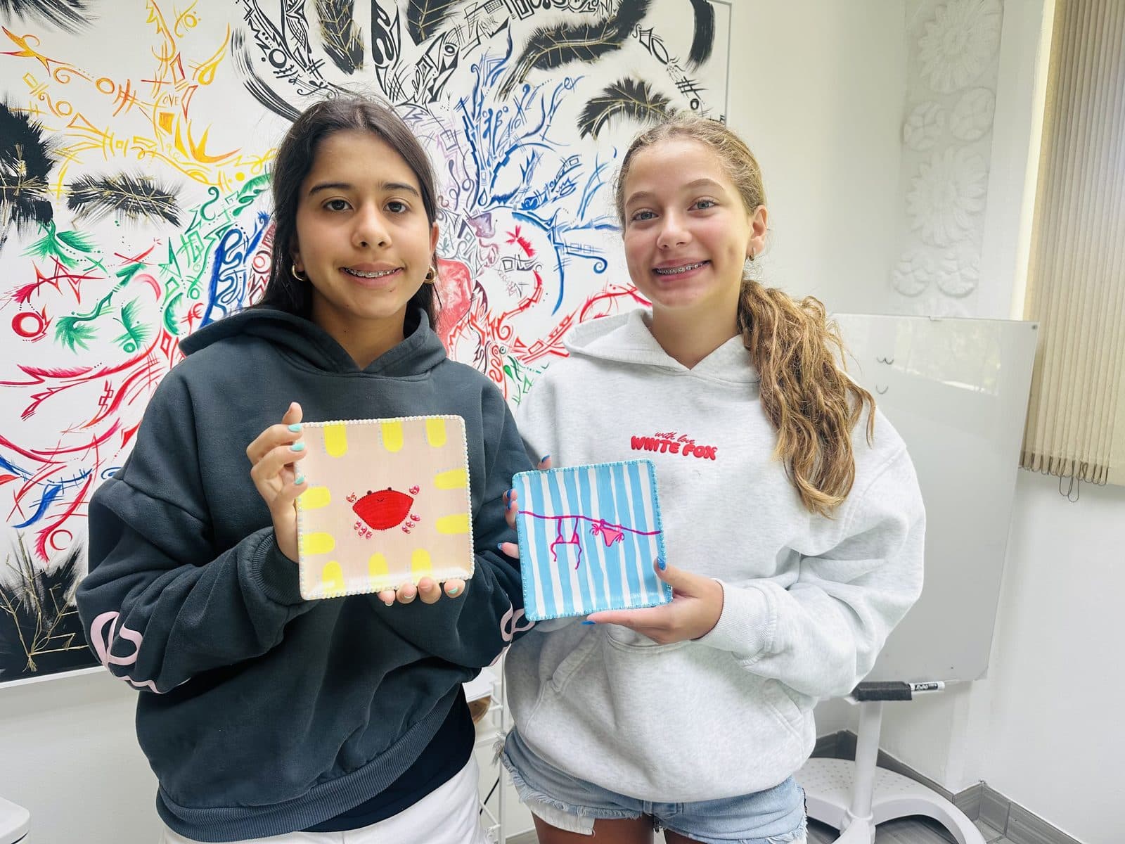 Two students showing the boxes they painted at the studio